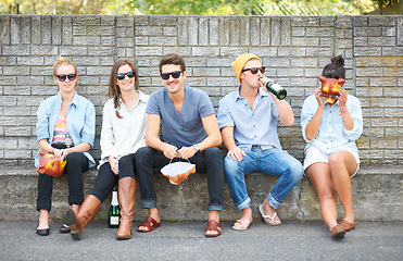 Image showing Drinks, portrait and friends on a bench in public for costume masks, conversation and bonding on the weekend. Happy, group and people in the city for alcohol, communication and together for society