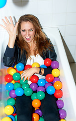 Image showing Portrait, throw ball and woman in bathtub for fashion, style and trendy hipster at home. Happy person in tub with color, sphere or plastic with body in bathroom, relax and cool clothes in Canada.