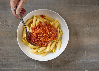 Image showing bologna sauce is added to a bowl of pasta