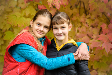 Image showing Close-up portrait of two girls of Slavic appearance in casual autumn clothes against the background of an autumn forest