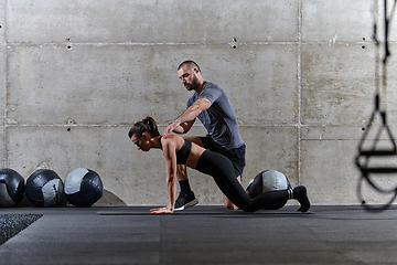 Image showing A muscular man assisting a fit woman in a modern gym as they engage in various body exercises and muscle stretches, showcasing their dedication to fitness and benefiting from teamwork and support