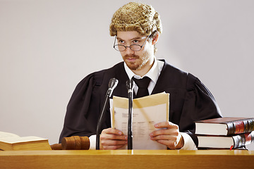 Image showing Legal, documents and a judge man in court with trial evidence for a verdict to punish crime. Law, justice and glasses with a serious lord justice listening to proof or testimony for criminal sentence