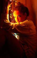 Image showing Christmas lights, portrait and young woman in a room for festive decoration for the holidays. Celebration, modern and female person from Canada relaxing or chilling in a modern apartment or home.