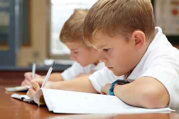 Image showing Young students, classroom and writing in books for education, thinking mindset or children on scholarship. Boys, school kids or learning with creative idea on desk, studying and test or work in class