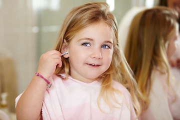 Image showing Grooming, hygiene and a child cleaning ears with an earbud in a home bathroom for sanitation. Smile, mirror and a girl or young kid learning to clean body during morning routine and getting ready