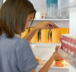 Image showing Woman in kitchen arranging food in fridge with care, ruler and ocd behavior, symmetry and anxiety. Intrusive thinking, pattern and girl packing refrigerator with measurement, order and mental health.