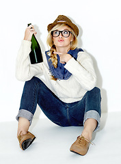 Image showing Champagne, drunk or relax with woman on floor in studio with hangover celebration, party or event. Pointing or female person drinking alcohol or beverage in bottle for New Year on white background