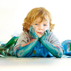 Image showing Messy, portrait and a child in paint after art in class, school or education on the floor. Happy, relax and a boy, kid or kindergarten student covered in color after painting, creativity or playing