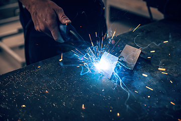 Image showing Male worker hand welding steel rack