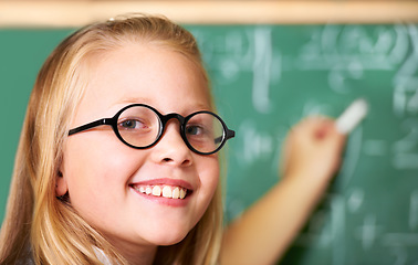 Image showing Portrait, nerd and happy kid writing on chalkboard in class for learning, education and study math. Face, glasses and smile of geek at school, cute girl child and student in classroom in Australia