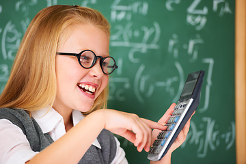 Image showing Child, calculator and happy for education, learning and problem solving or solution on chalkboard. Smart student, kid or girl with glasses and excited for school, typing numbers and math in classroom