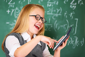 Image showing Girl, calculator and happy for education, learning and problem solving or solution on chalkboard. Smart student, kid or child with glasses and excited for school, typing numbers and math in classroom