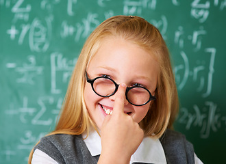 Image showing Girl child, student with glasses and chalkboard for learning, education and to start math quiz in classroom. Happy face of smart, intelligent kid with vision, eye care and numbers on board for school