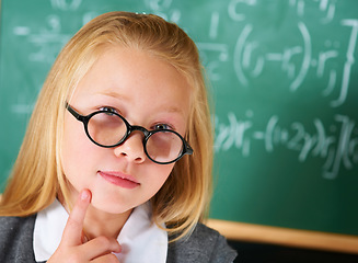 Image showing Portrait of student, nerd and child thinking by chalkboard for learning knowledge, education or study math. Serious face, glasses and geek at school, ginger girl or kid in classroom in Switzerland