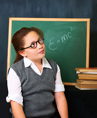 Image showing Thinking, solution and child student in classroom with idea, problem solving or brainstorming facel expression. Smile, education and young girl kid with glasses for learn or plan with board in school