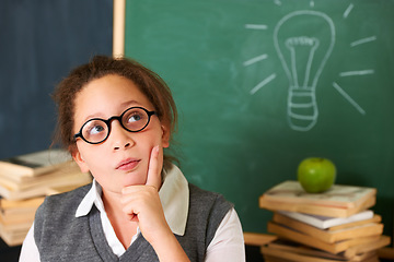Image showing Child, thinking and lightbulb on chalkboard for education, learning and knowledge with ideas or solution in classroom. Girl, student or school kid for vision, drawing inspiration on board or remember