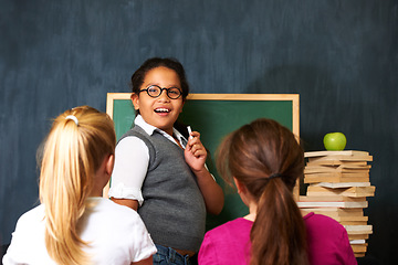 Image showing Teaching, smile and portrait of kid student by board for lesson, knowledge or education with friends. Happy, glasses and girl child talking and writing with chalk for classmates in school or academy.