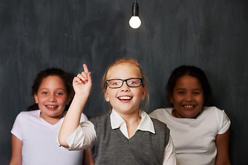 Image showing Light bulb, smile and children with idea, solution or thinking facial expression by a black background. Happy, excited and portrait of group of kid girl friends with plan, decision or choice together