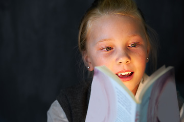 Image showing Smile, reading and child student with book in classroom for knowledge, learning or education. Happy, excited and young girl kid enjoy a story, fantasy or novel at school or academy in the dark.