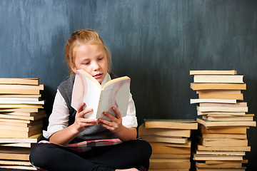 Image showing Girl, classroom and child reading book for education, language learning and knowledge on chalkboard background. Kid or student on floor with books, library and story for school, English or literature