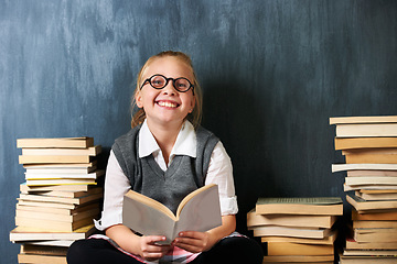 Image showing Girl, chalkboard and child reading book for education, language learning and knowledge in classroom. Kid or student on floor with books, glasses and happy for school, English and literature portrait