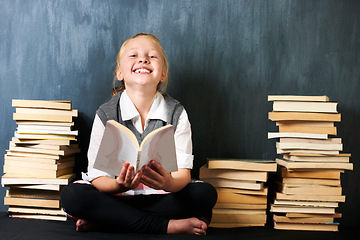 Image showing Girl, classroom and kid reading book for education, language learning and knowledge on chalkboard background. Child or student on floor with books and story for school, English or literature portrait