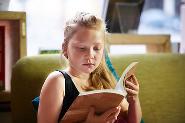 Image showing Relax, reading and child student with a book in living room for education, learning or knowledge. Study, nerd and girl kid enjoying a story, fantasy or novel in the lounge at modern home or house.