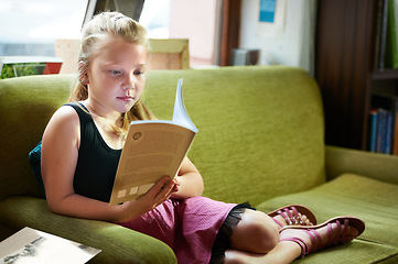 Image showing Kid, girl on sofa and reading book for home learning, education and story with knowledge or creative mind. Child relax on couch with literature, English language and library novel in living room