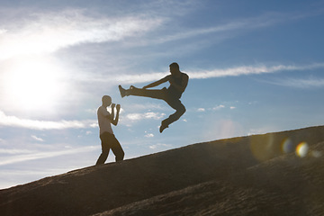 Image showing Jump, kick and karate men on mountain top for fitness, training or body, speed or power on blue sky background. Martial arts, taekwondo or MMA friends workout in nature for cardio, exercise or sports
