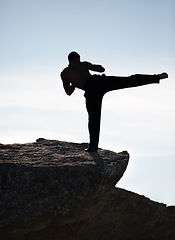 Image showing Karate, kick and fitness man on mountain top for body, power or defense training on blue sky background. Martial arts, MMA and male taekwondo master in nature for exercise, sports or morning cardio