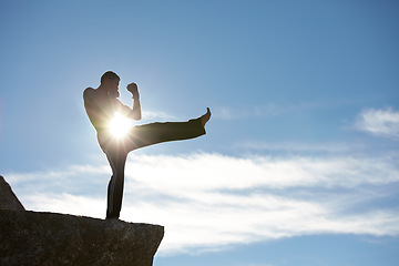 Image showing Fitness, kick and karate man on mountain top for body, power or defense training on blue sky background. Martial arts, MMA and male taekwondo master in nature for exercise, sports or morning cardio