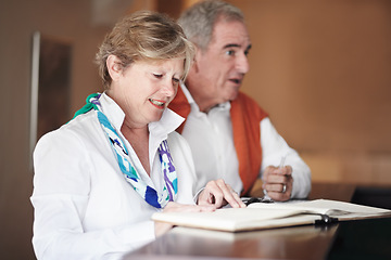 Image showing Senior couple, reading and signing documents at hotel reception desk for booking, reservation or vacation. Mature man and woman filling forms, application or checking paperwork or sign in at resort