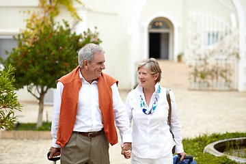 Image showing Holding hands, smile and old couple outside hotel, villa and luggage on luxury retirement vacation together. Marriage, travel and holiday, senior man and woman with suitcase walking in courtyard.