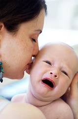 Image showing Kiss, care and a mother with a crying baby for love, bonding and nurture in the bedroom of a house. Sad, fear and a mom with affection for a newborn or tired kid with emotion, frustrted or fatigue