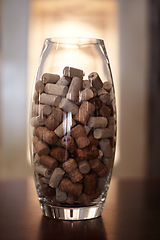 Image showing Winery, glass and jar with a group of cork plugs on a wooden table closeup for decoration or preservation. Background, texture and interior design with stopper seals in a vase for sustainability
