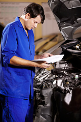 Image showing Paperwork, man and mechanic reading at engine of car, repair and maintenance. Checklist, technician and serious person on motor vehicle hood, inspection list and fix transport at auto service garage