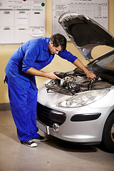 Image showing Car, service and diagnostic with a mechanic man in a workshop as an engineer looking at an engine of a vehicle. Garage, repair or quote with a young technician working under the hood of an automobile