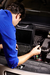 Image showing Car, diagnostic or repair and a mechanic man in a workshop as an engineer looking at the engine of a vehicle. Garage, report or service with a young technician working under the hood of an automobile