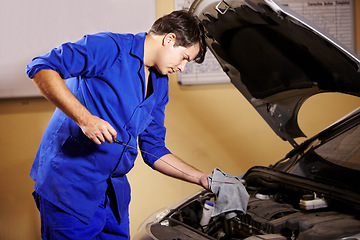 Image showing Mechanic, oil and service with a man in a workshop to fix or repair a vehicle during routine maintenance. Engineer, inspection and labor with a young person working in a garage for car assessment