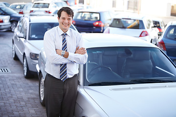 Image showing Portrait, luxury and a man arms crossed at a dealership for car sale in a commercial parking lot. Business, smile and automobile trade with a happy young salesman outdoor for transport service