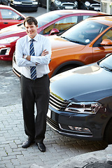 Image showing Portrait, smile and a man arms crossed in a parking lot for car sale at a commercial dealership. Business, luxury and automobile trade with a happy young salesman outdoor for transport rental