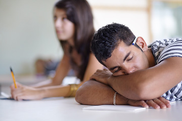 Image showing Tired, sleeping and a bored man in a classroom for learning, education and university burnout. Mental health, campus and a male student at a desk for rest, stress or fatigue in a college lecture