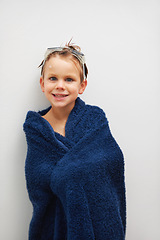 Image showing Portrait, bath and a boy in a towel in studio on a white background to dry after cleaning for hygiene. Children, smile and a happy young kid in the bathroom of his home for skincare or wellness