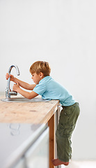 Image showing Children, fantasy and a child in the kitchen sink, playing a game in his home as a plumber character. Kids, basin and counter with a curious young boy in a modern apartment for imaginary plumbing
