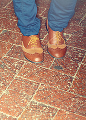 Image showing Shoes, fashion and closeup of man feet by brick floor for an elegant, stylish and trendy outfit. Legs, footwear and zoom of male person with luxury, classy and expensive style with jeans by pavement.