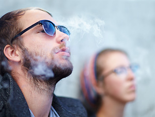 Image showing Face, man and woman smoking outdoor with sunglasses for experience, relax and cigarette enjoyment. People, hipster and smoke for trend, exhale or tobacco satisfaction with shades and confidence