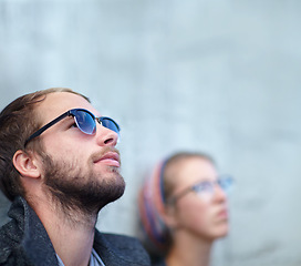 Image showing Thinking, man and city with sunglasses for relax, peace and idea outdoor against wall with eyewear. Couple, people and thoughtful with memory, remember and leaning with shades and casual smile