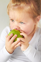 Image showing Baby, hungry girl and eating apple with thinking, learning and nutrition for growth in childhood at family home. Infant child, toddler and biting green fruit for health, wellness and diet in house