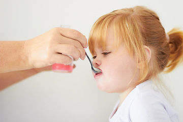 Image showing Girl child, hand and spoon with medicine for healthcare, wellness or help from parent in house. Baby, infant kid or toddler with person, bottle and pharma drugs for vitamin c, immune system or growth