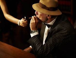 Image showing Businessman, mafia and hold for cigarette in office with woman for light. Gangster, mob or person in suit, bowtie and hat for meeting, criminal activity or job with tobacco for relaxation in space